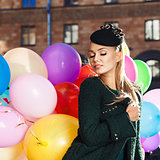 beautiful lady in retro outfit holding a bunch of balloons in ci