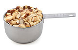 Chopped brazil nuts in a metal cup measure