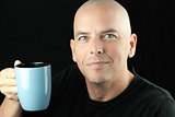 Peaceful bald man lifts mug to camera