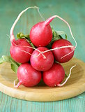 bunch of fresh organic radishes on wooden plate