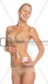Young woman in lingerie applying creme on belly