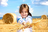 small rural girl on harvest field with straw bales