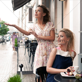 two beautiful young girls in summer outfit have lunch at the tab