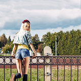 Blonde girl in short denim shorts with roses wreath on head