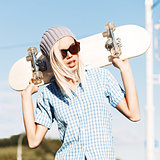 Beautiful blonde girl in short shorts with skateboard