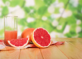 Glass of grapefruit juice and sliced ​​on table in yard