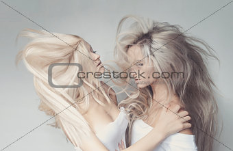 grey and blond haired girls friends laughing and hug