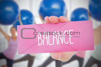 Woman holding pink card saying balance