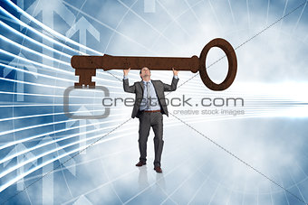 Composite image of businessman carrying large key with arms raised