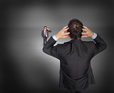 Composite image of stressed businessman with hands on head with tiny businessman