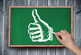 Composite image of hand drawing thumbs up with chalk