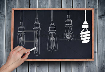 Composite image of hand drawing light bulbs with chalk
