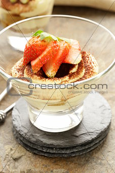 Italian dessert tiramisu decorated with strawberries in a glass beaker