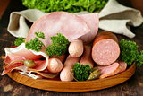 various kinds of sausages and smoked bacon on the wooden plate