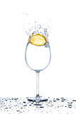 Lemon splashing into glass of water on white background
