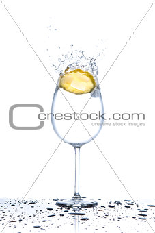 Lemon splashing into glass of water on white background