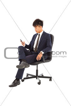 Young businessman sitting in a chair and watching smartphone