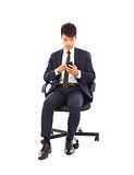 handsome businessman touching smart phone on chair