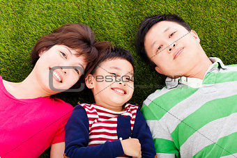 happy parents and son lying on a meadow