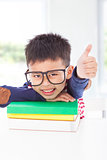 little boy lying on books and thumb up