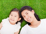  smiling mother and daughter lying on a meadow