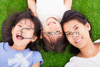 happy mother and daughters lying on a meadow