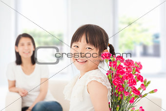  little girl looking back and hiding a bouquet of carnations