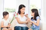 two daughters handing mother carnations 