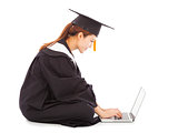 female graduation sitting and  typing on a laptop