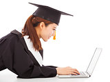 female graduation lying on floor and using a laptop