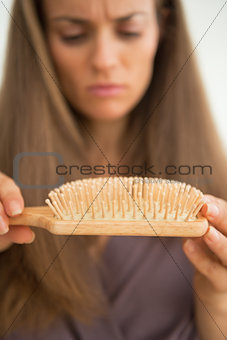 Closeup on concerned young woman looking on hair comb