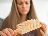 Closeup on concerned young woman looking on hair comb