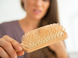 Closeup on stressed young woman looking on hair comb