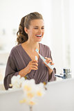 Happy young woman with toothbrush in bathroom
