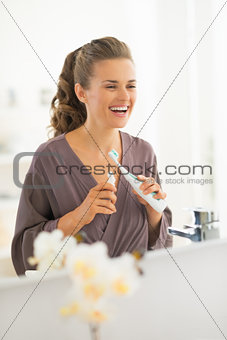 Happy young woman with toothbrush in bathroom