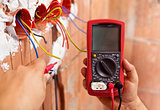 Electrician hands with multimeter and wires