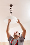 Man screwing a new lightbulb into ceiling lamp