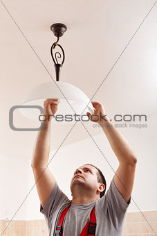 Man screwing a new lightbulb into ceiling lamp