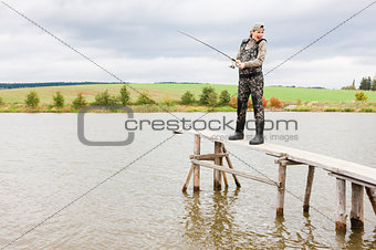 woman fishing on pier at pond