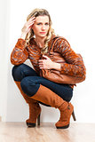 sitting woman wearing fashionable brown boots holding a handbag