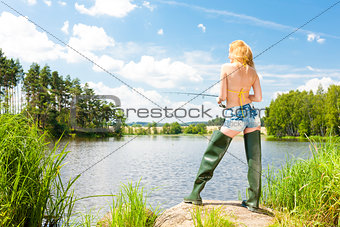 young woman fishing at pond in summer
