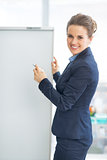 Happy business woman writing in flipchart