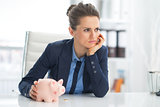 Thoughtful business woman piggy bank with