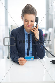 Business woman with credit card talking phone