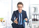 Smiling realtor woman with keys stretching hand for handshake