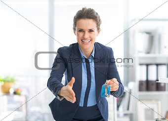 Smiling realtor woman with keys stretching hand for handshake