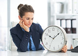 Thoughtful business woman looking on clock