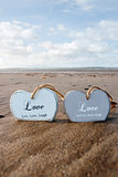 two inscribed wooden love hearts in the sand