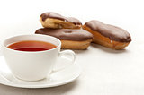 cup of tea and vanilla eclairs with chocolate frosting