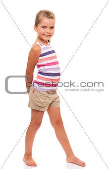 cute little girl standing on white holding hands behind back
